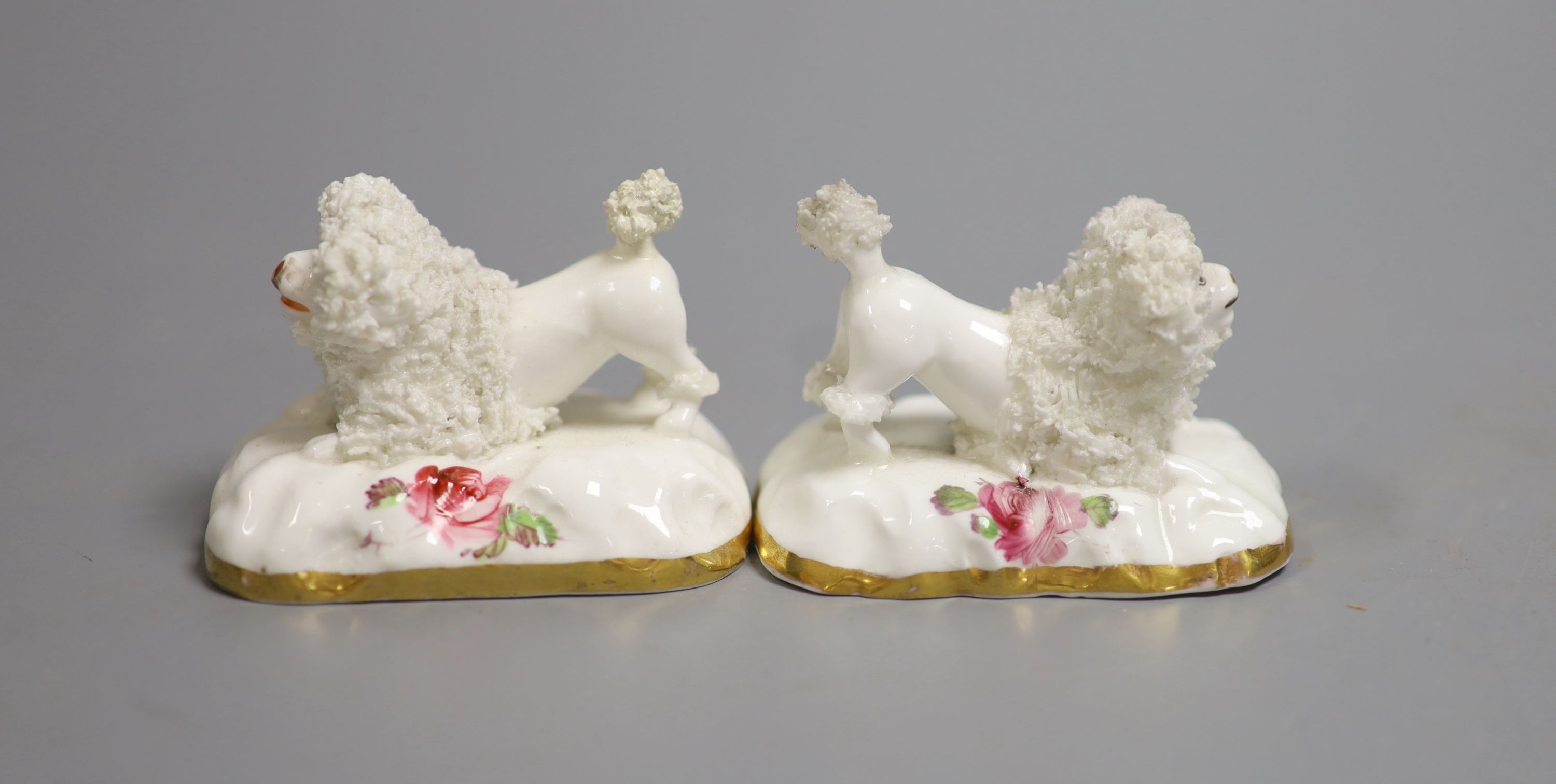 A pair of Staffordshire porcelain models of begging poodles, c.1830-50, each on a pink rose painted base, 6.8 cm long